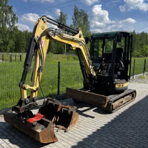 Żółta minikoparka na białej kostce
